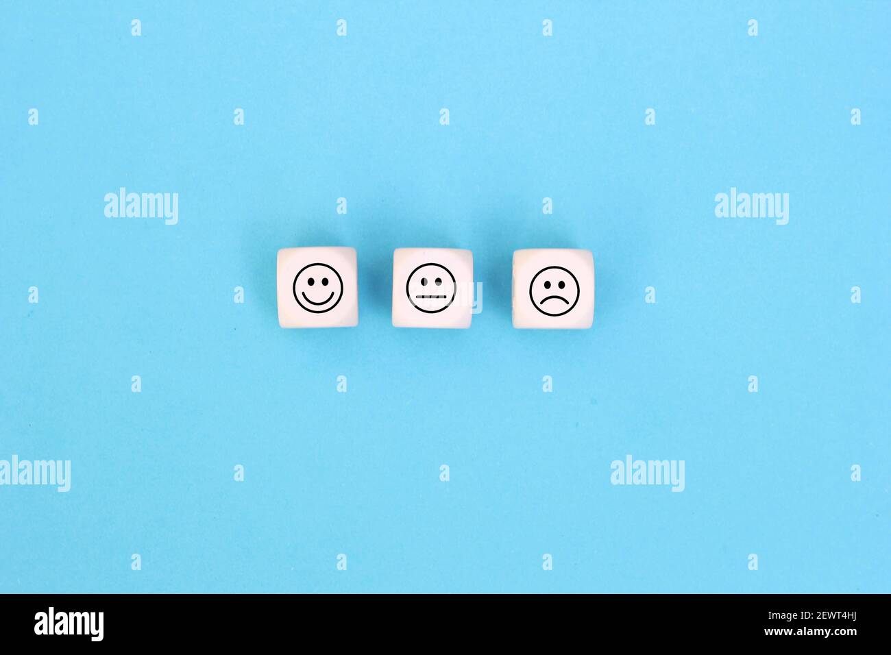 Happy sad and neutral smile faces on wooden blocks on Blue background. Customer satisfaction, evaluation or feedback concept. Stock Photo