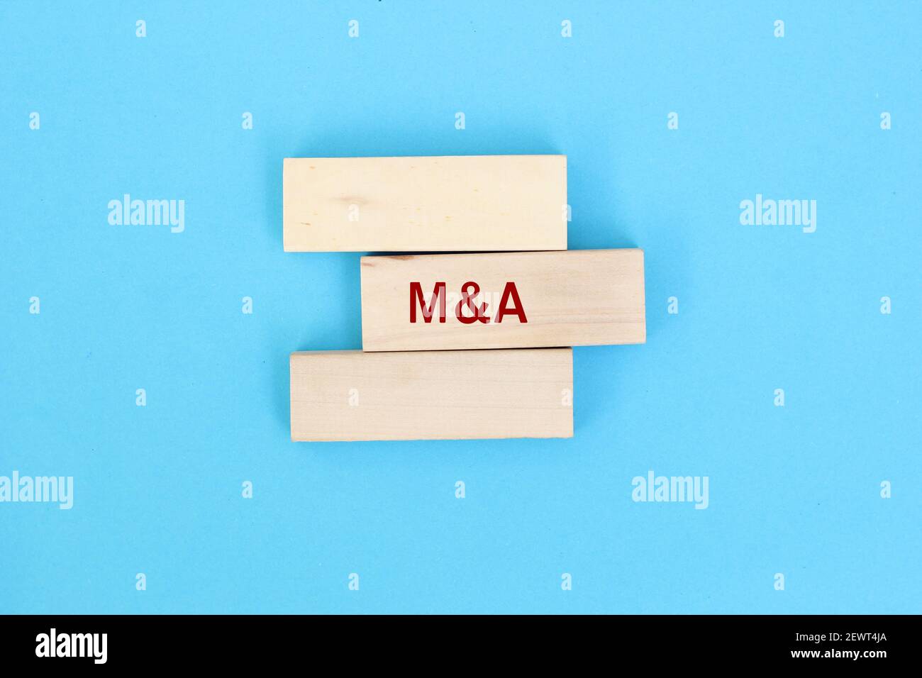 M and A merger and acquisitions concept. Male human hand pushing the wooden block with the word M and A and completing the merger process. Stock Photo