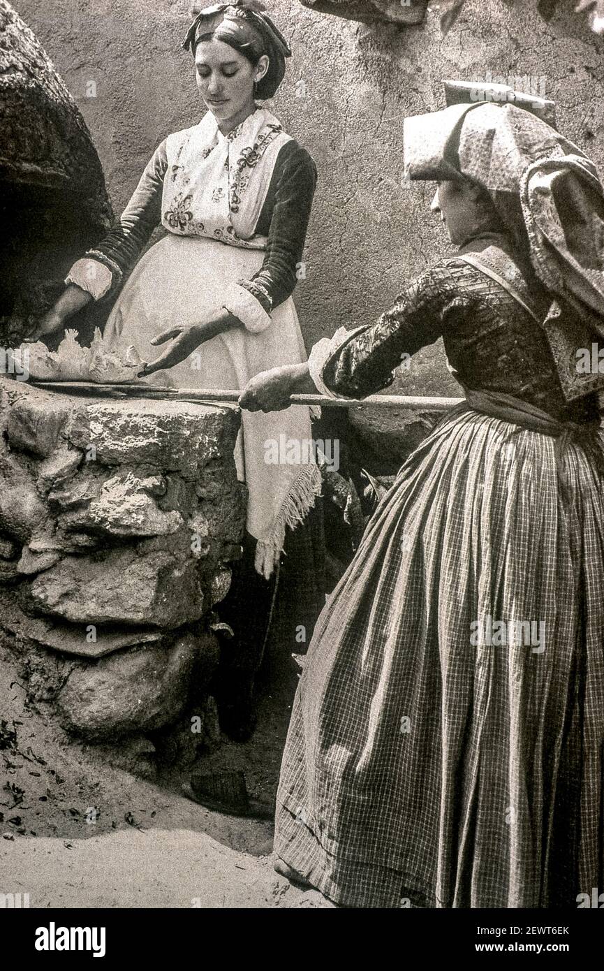 Ancient Photo - depicting 2 women in front of the bread oven in typical Sardinian clothes Stock Photo