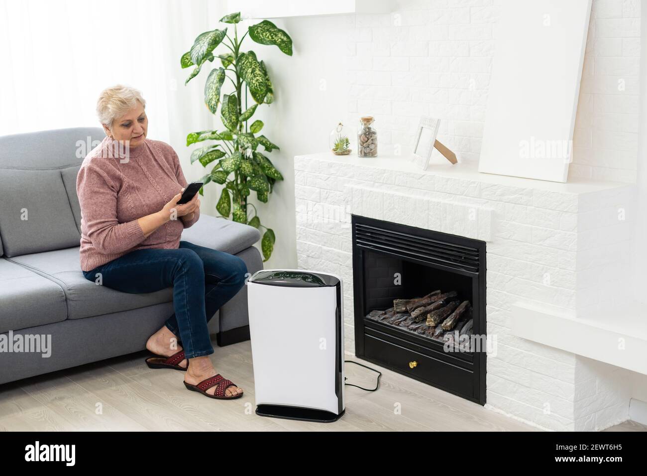 an elderly woman uses an air purifier Stock Photo Alamy