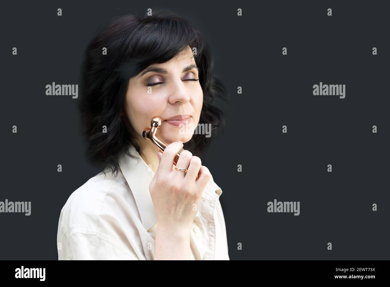 Woman smoothes folds and wrinkles on the skin with a facial massager. Stock Photo