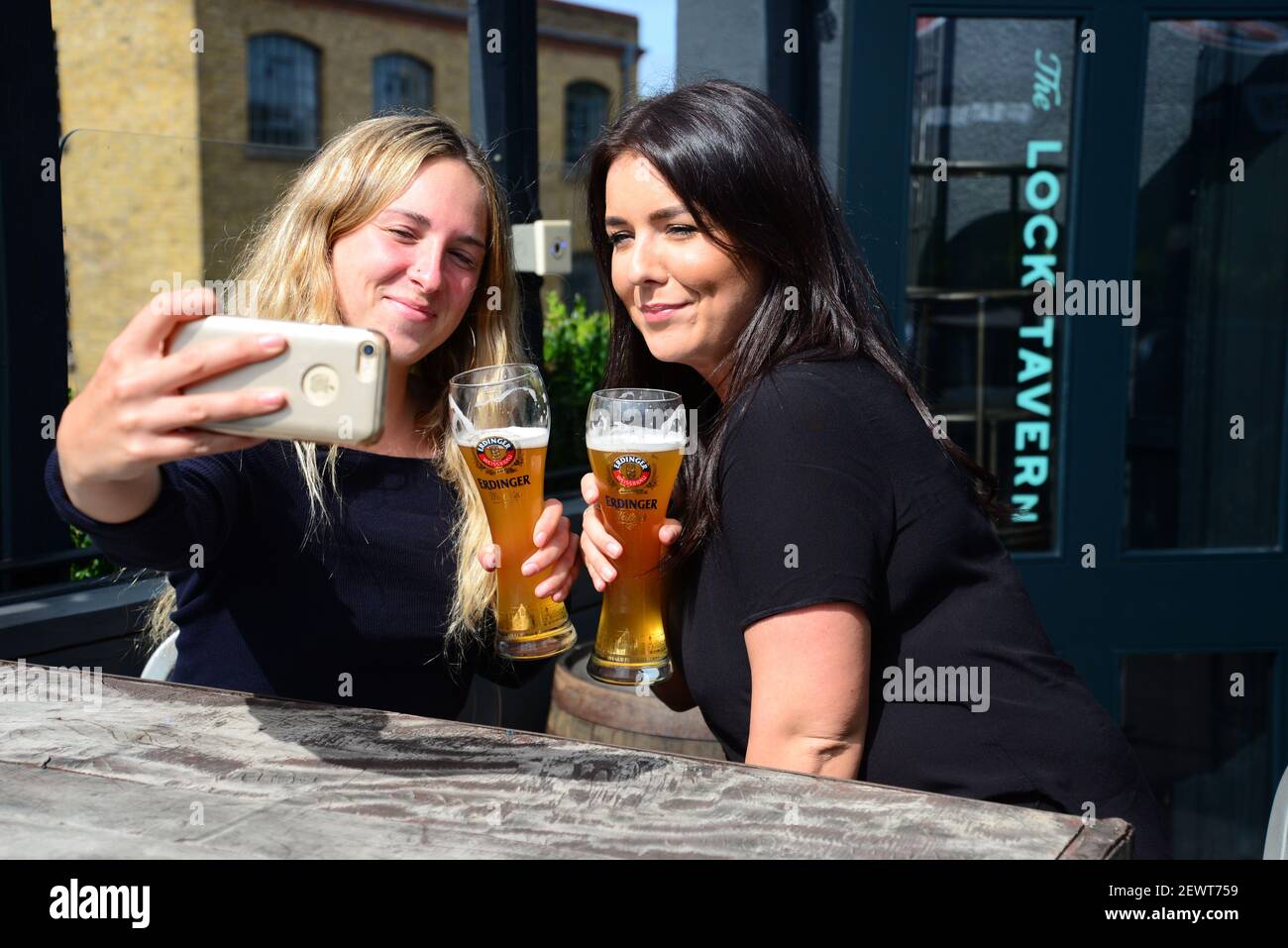 Two women drinking beer whilst taking a selfie in a London pub Stock Photo