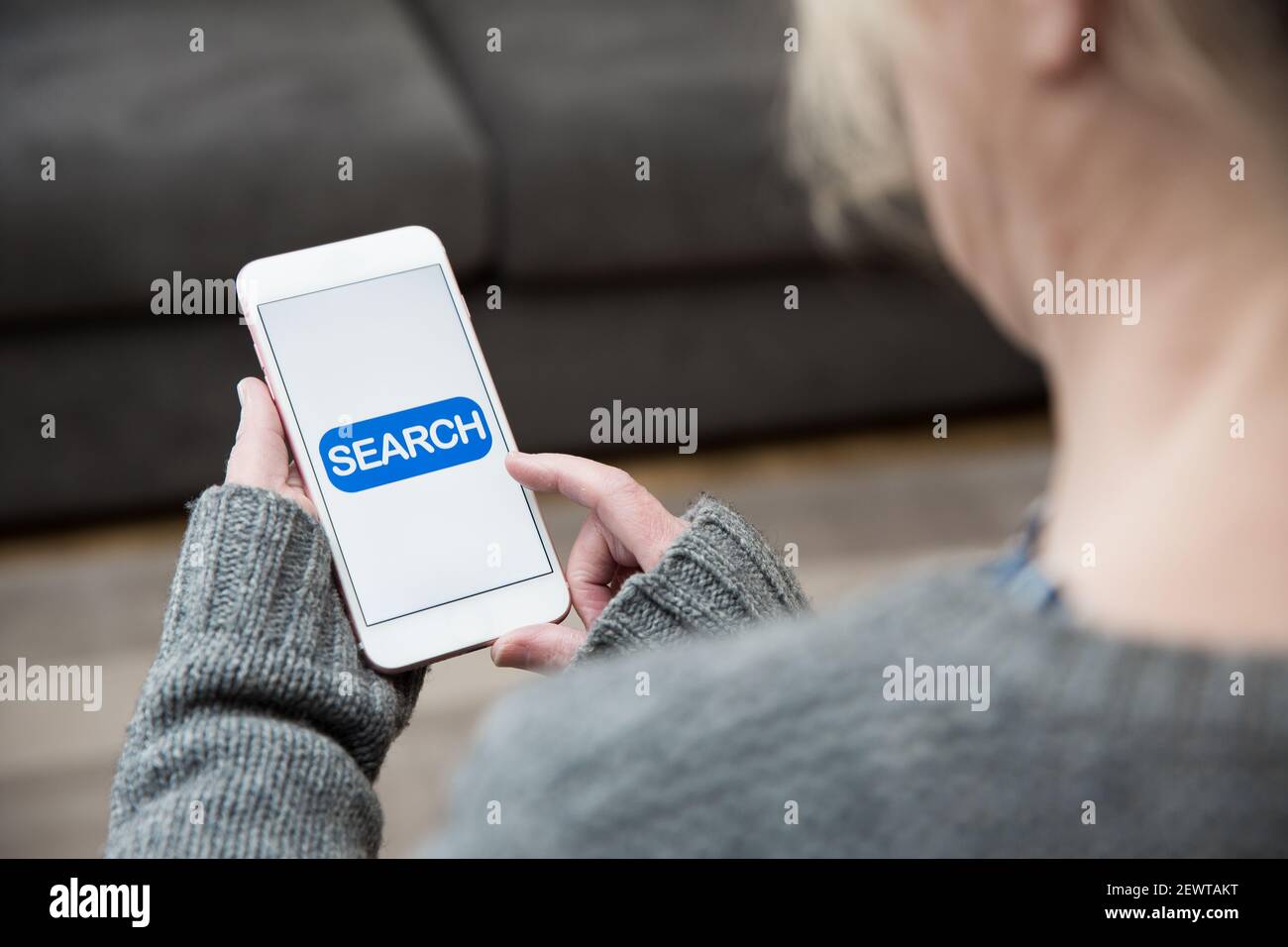 A woman tapping a search icon on her mobile phone whilst looking for online content information Stock Photo