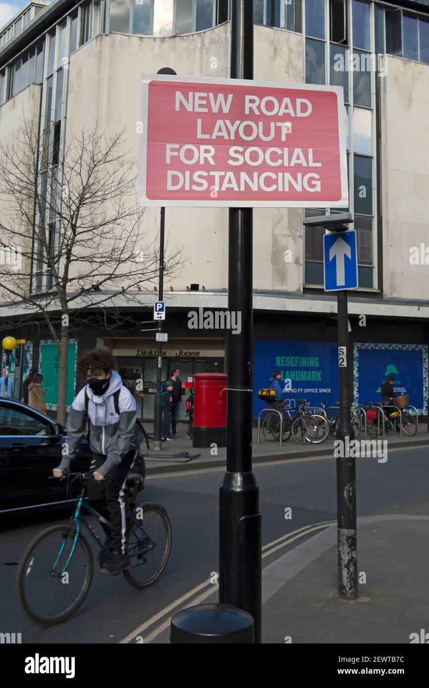 cyclist in mask passes a red and white sign indicating a new road layout to allow covid 19 related social distancing, richmond, surrey, england Stock Photo