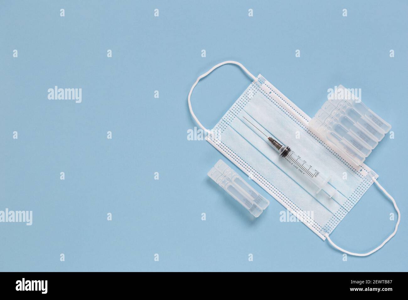 Protective face masks, ampullas with vaccine and expendable syringe for vaccination. Treatment concept various infection and virus diseases. Stock Photo