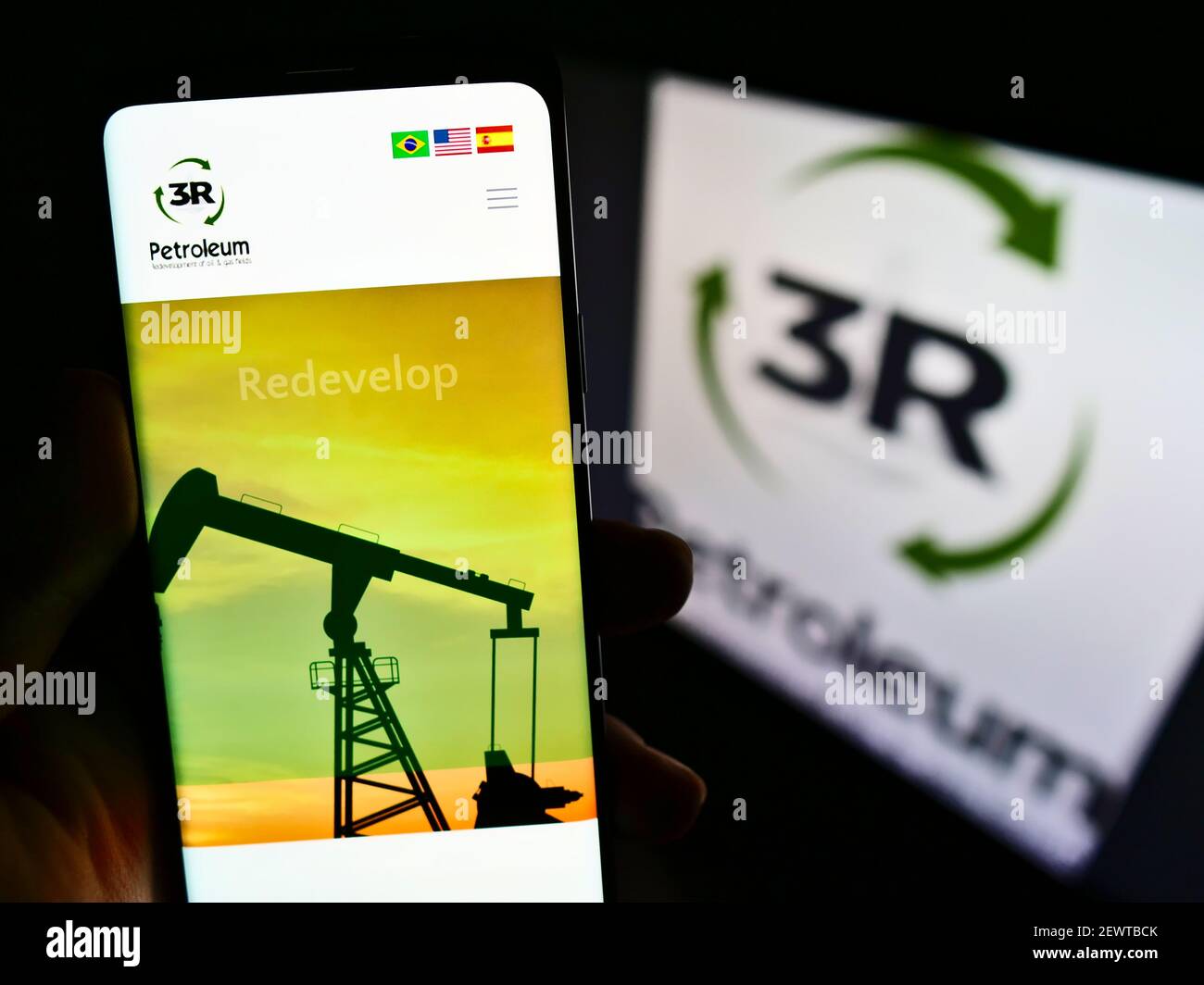 Person holding cellphone with web page of Brazilian oil and gas company 3R Petroleum SA on screen in front of logo. Focus on center of phone display. Stock Photo