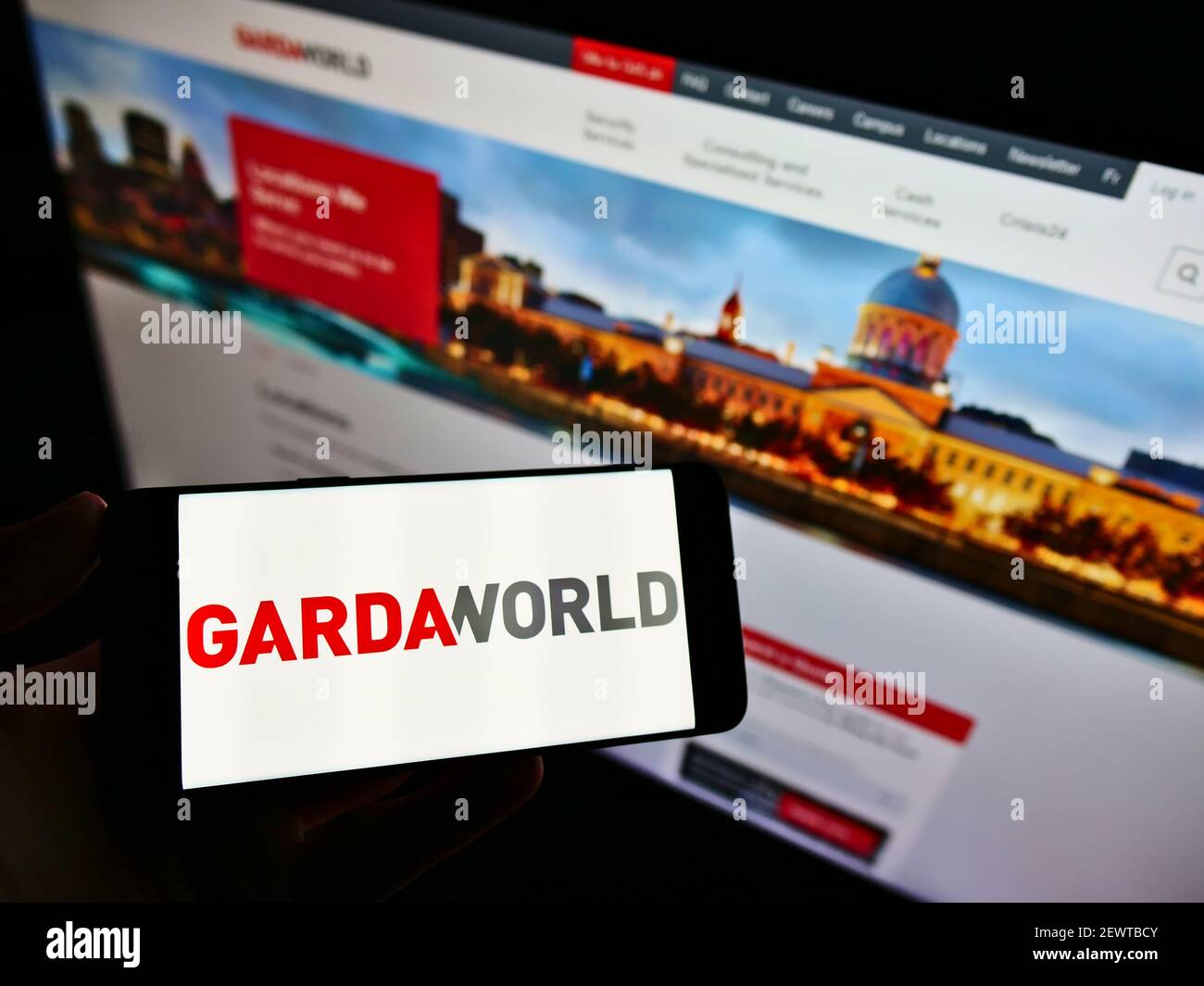 Person holding cellphone with business logo of Canadian private security firm GardaWorld on screen in front of website. Focus on smartphone display. Stock Photo