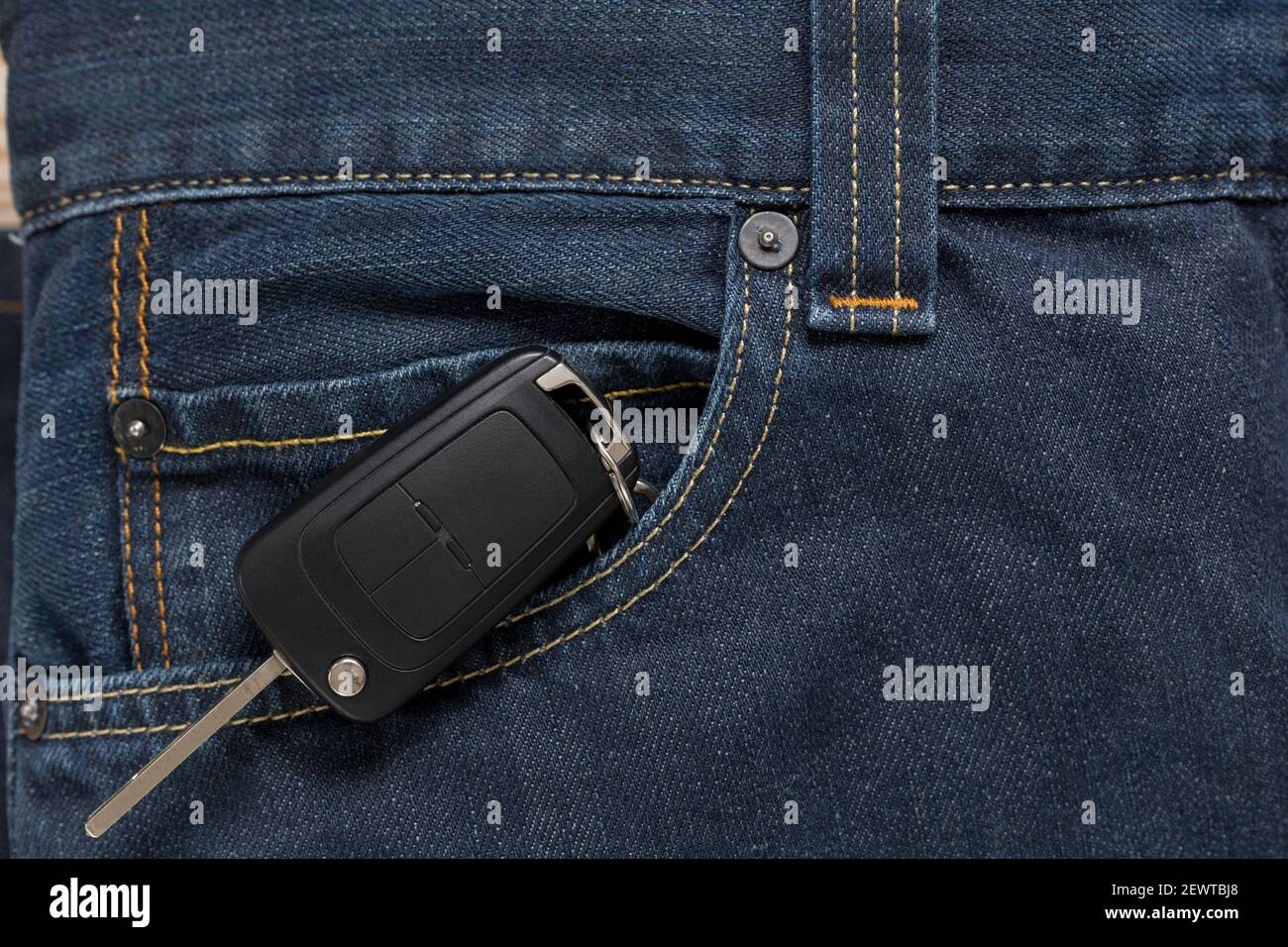 Ignition key is lying in side pocket of blue jeans. Modern lifestyle. Stock Photo