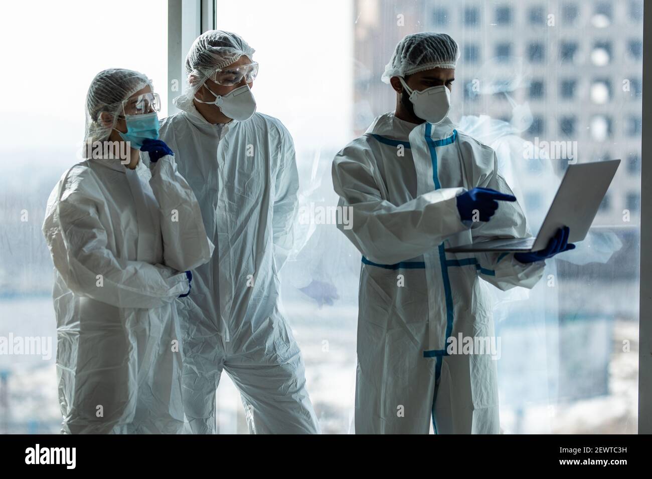Medical scientist in hazmat suit working laptop computer inside ...