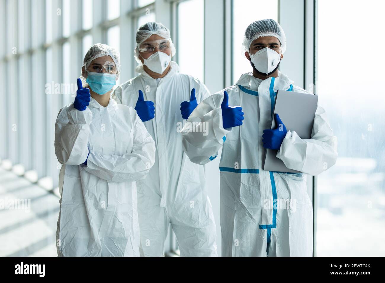 Multiracial medical workers with thumbs up while wearing surgical face