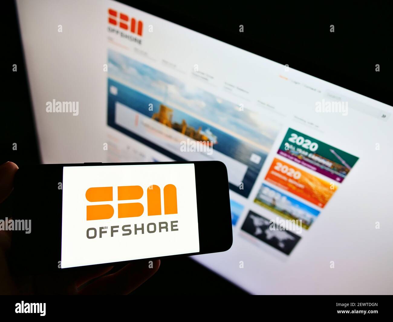 Person holding smartphone with logo of Dutch oil and gas company SBM Offshore N.V. on screen in front of website. Focus on phone display. Stock Photo