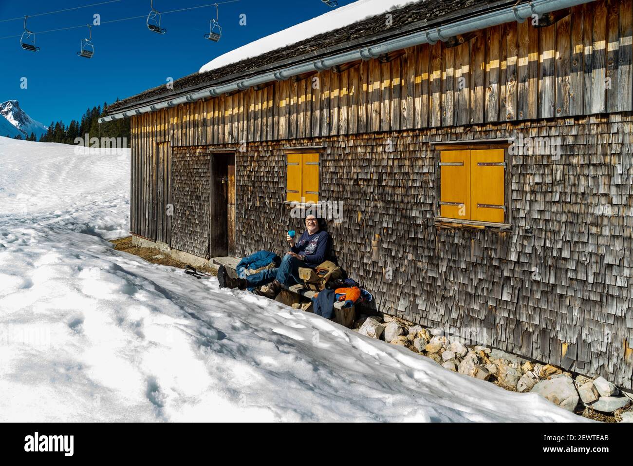 Pause auf der Bank an einer geschindelten Alphütte. Break on the bench at a shingled alpine hut. Wintersport in Austria's snow-covered alps. snowshoe Stock Photo