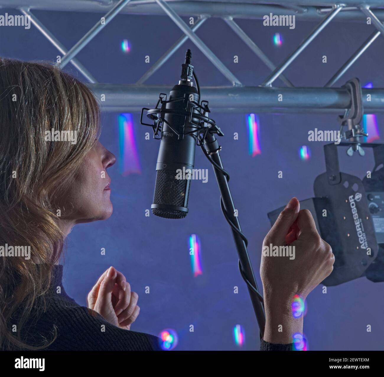 woman dancing and singing in microphone in front of the lights Stock Photo