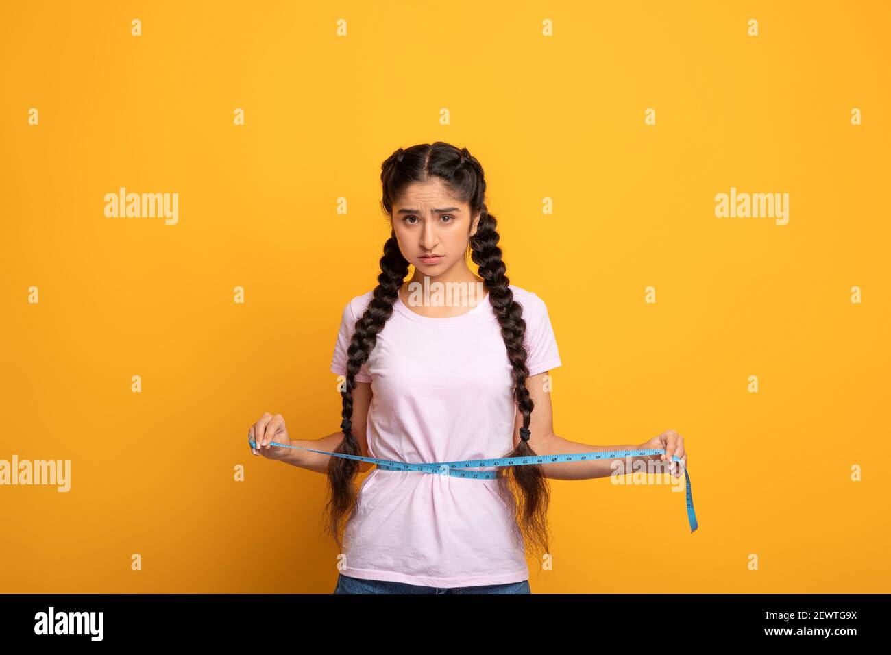 Sad Indian Woman Measuring Waist With Tape. Slimming Concept Stock Photo