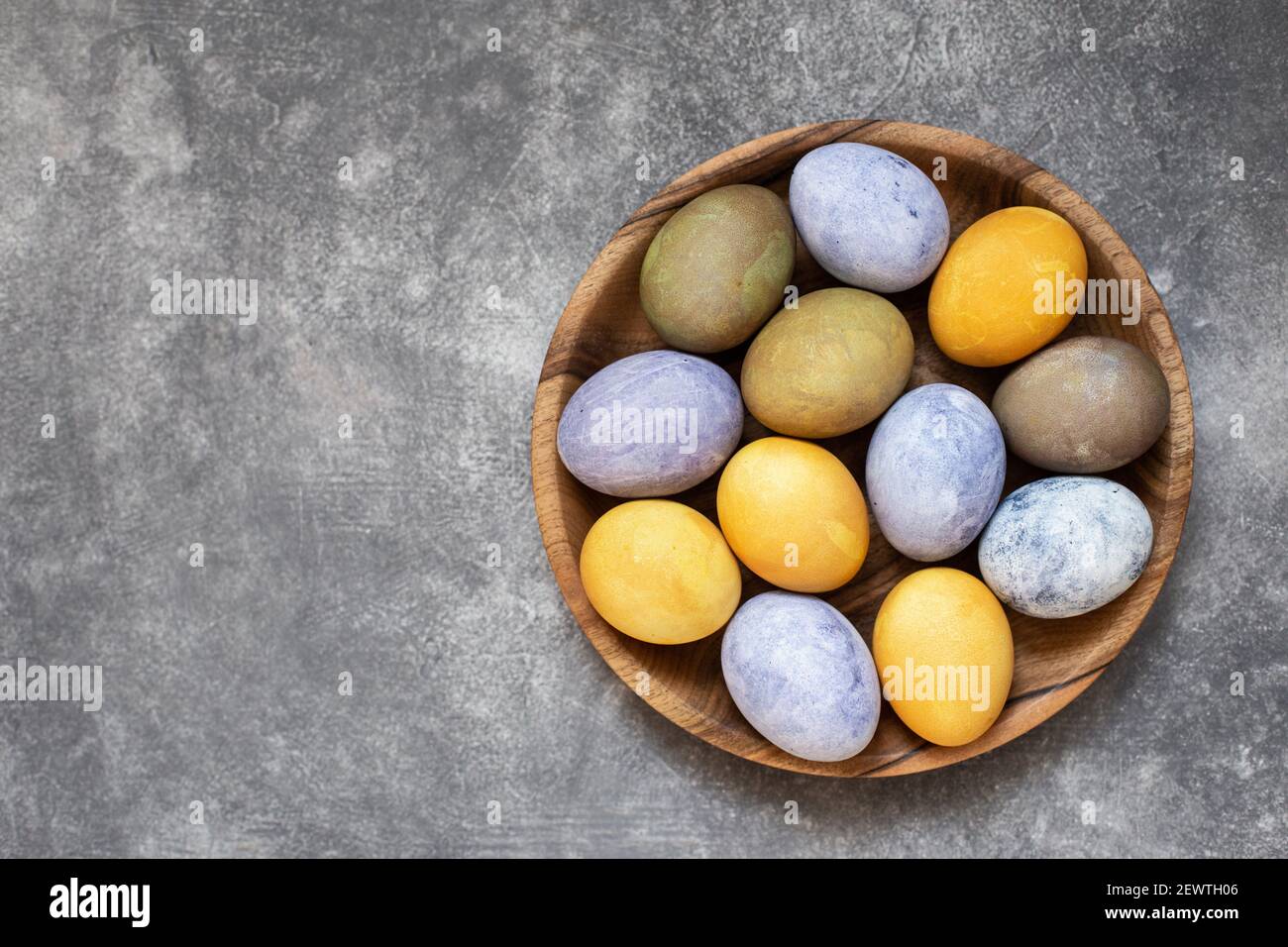 Easter eggs on wooden plate painted with natural dyes. Top view, close up. Stock Photo