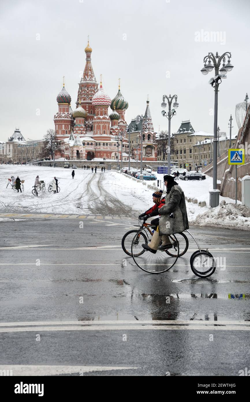 = Riding Vintage Bicycles at Basil’s Slope =  Father and son ride on vintage bicycles on Kremlin Embankment in the background of St. Basil’s Cathedral Stock Photo