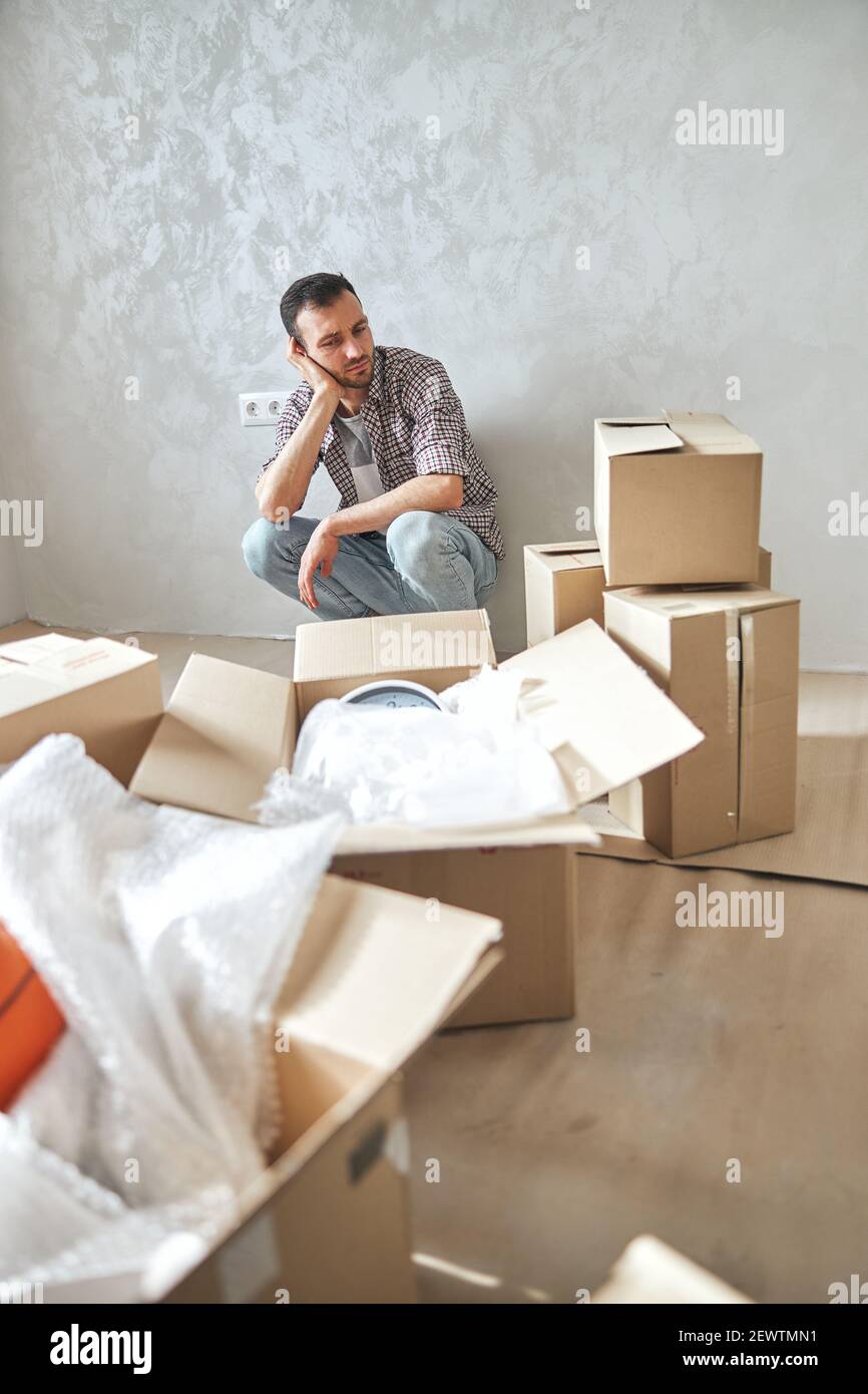 Low-spirited young man sitting in his new flat Stock Photo