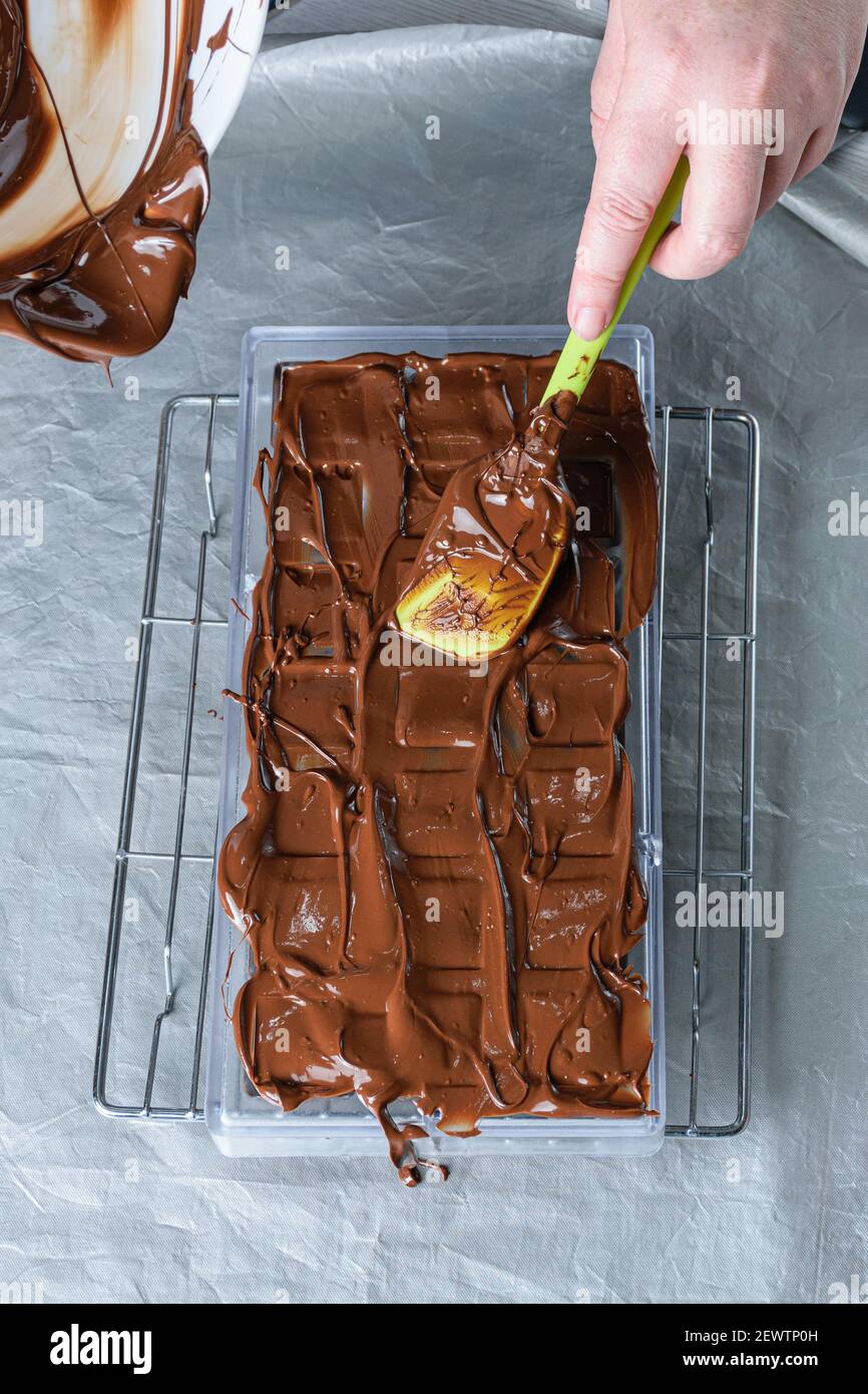 Confectioner using a spatula to place the tempered chocolate in a polycarbonate form. Stock Photo