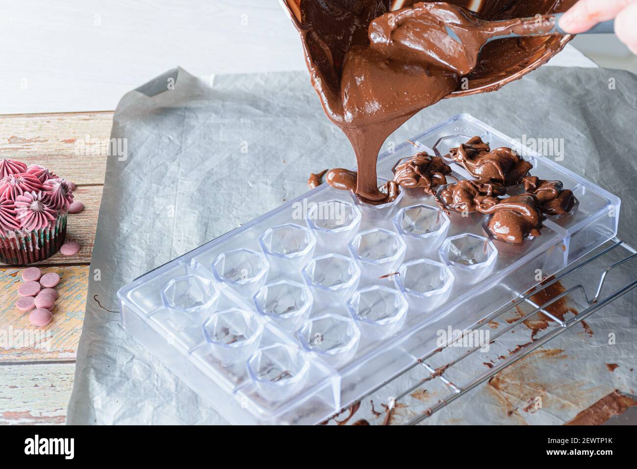 Closeup of confectioner pouring tempered chocolate in a polycarbonate form. Stock Photo