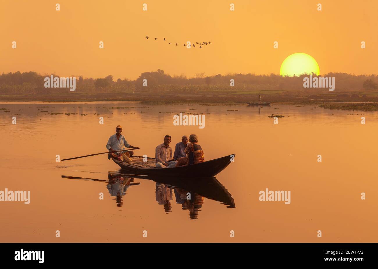 Family take a river boat ride at sunset with rural landscape at West Bengal, India Stock Photo