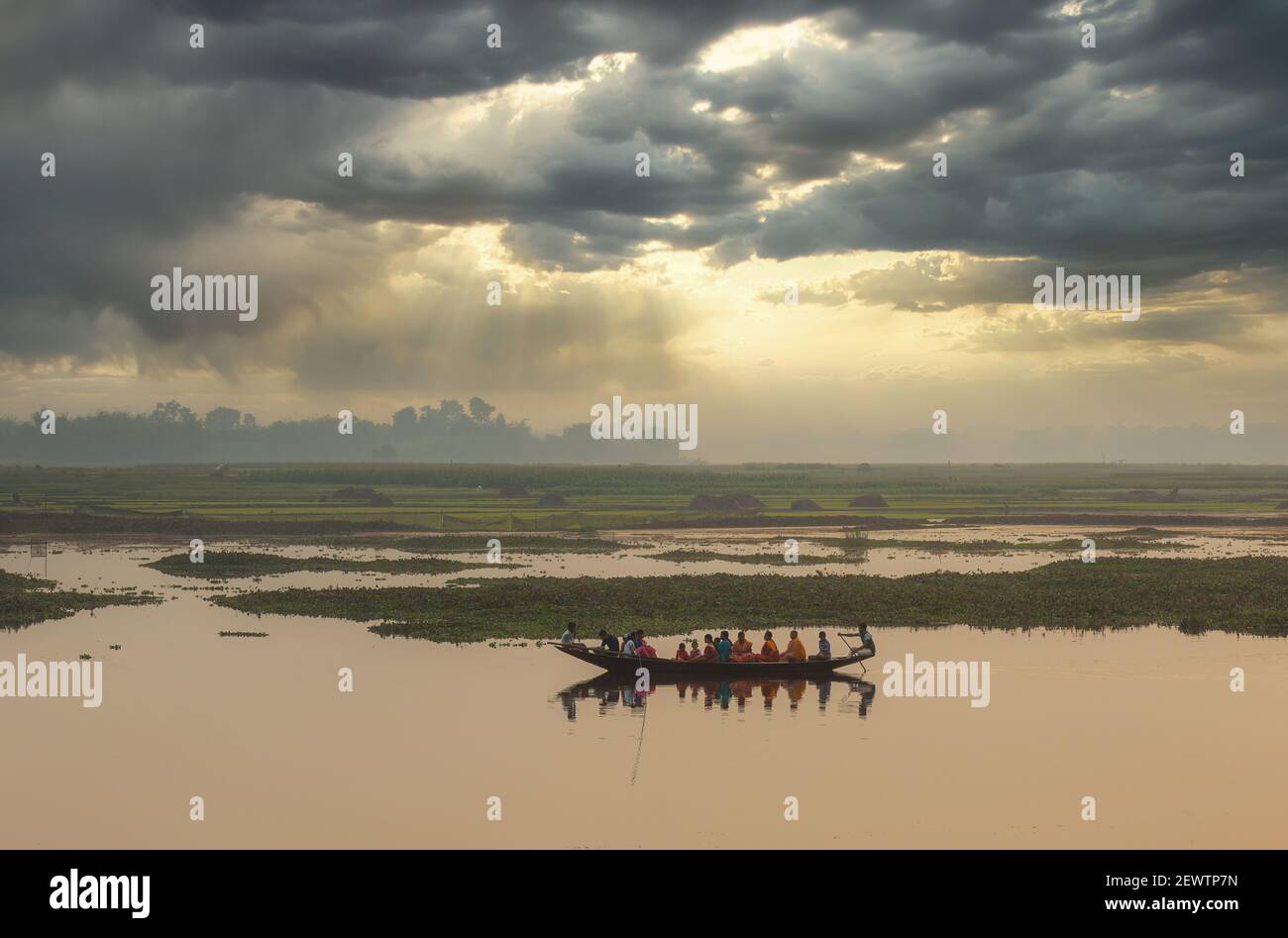 People take ferry ride on a river with rural landscape view at sunset at a village in West Bengal, India Stock Photo