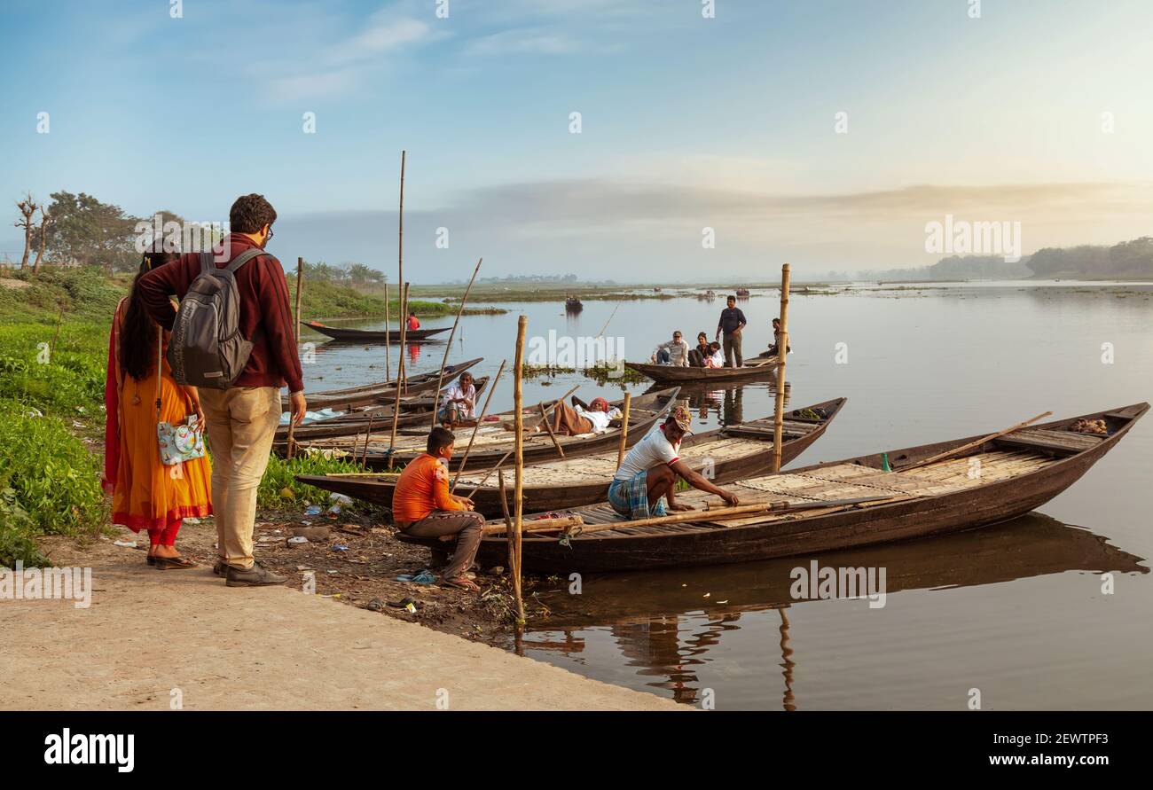Tourist couple waiting for a river boat ride at sunset at a village in West Bengal, India Stock Photo