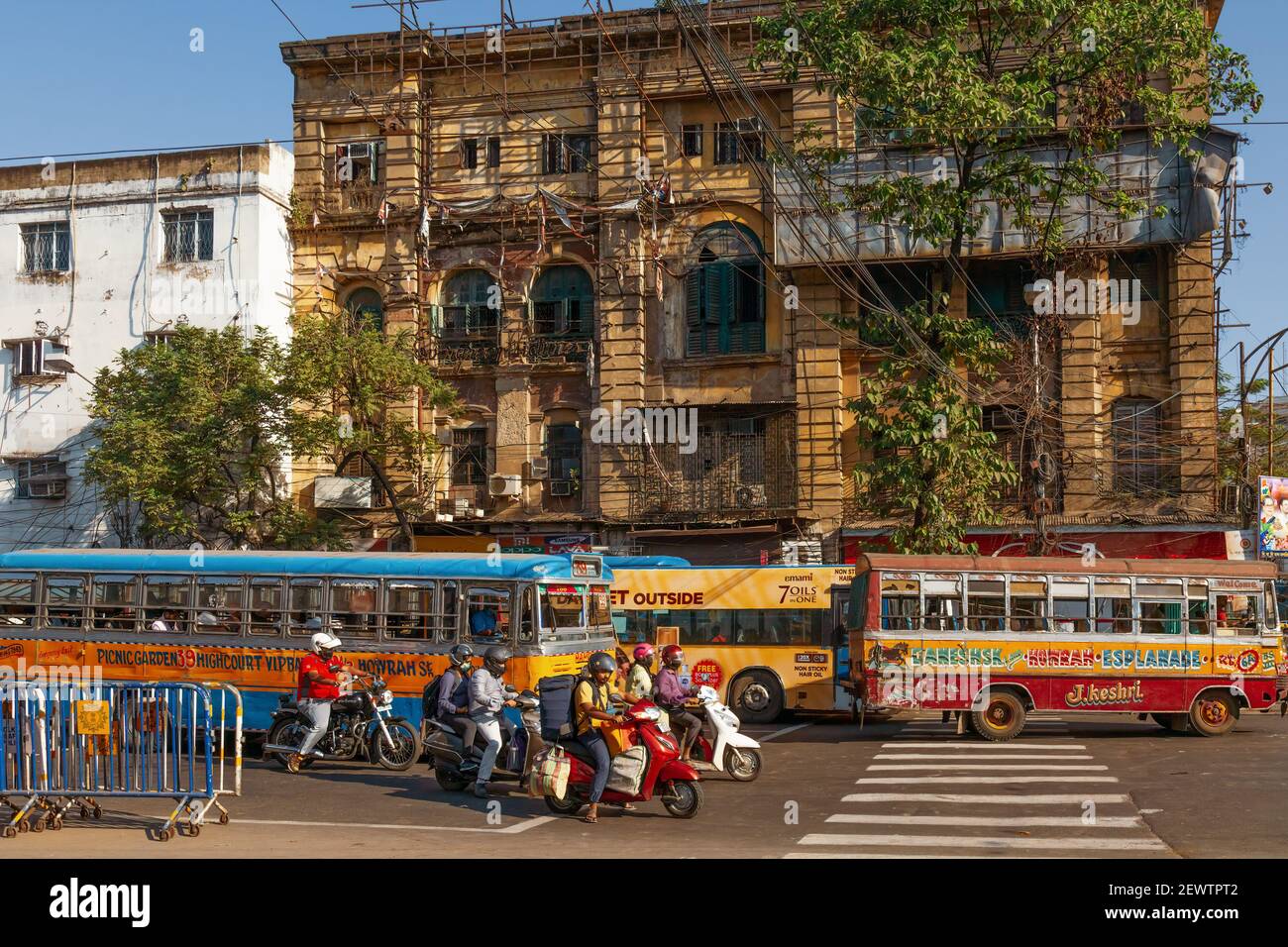 Public transport vehicles with commuters at city road crossing with old heritage buildings at Esplanade Kolkata Stock Photo