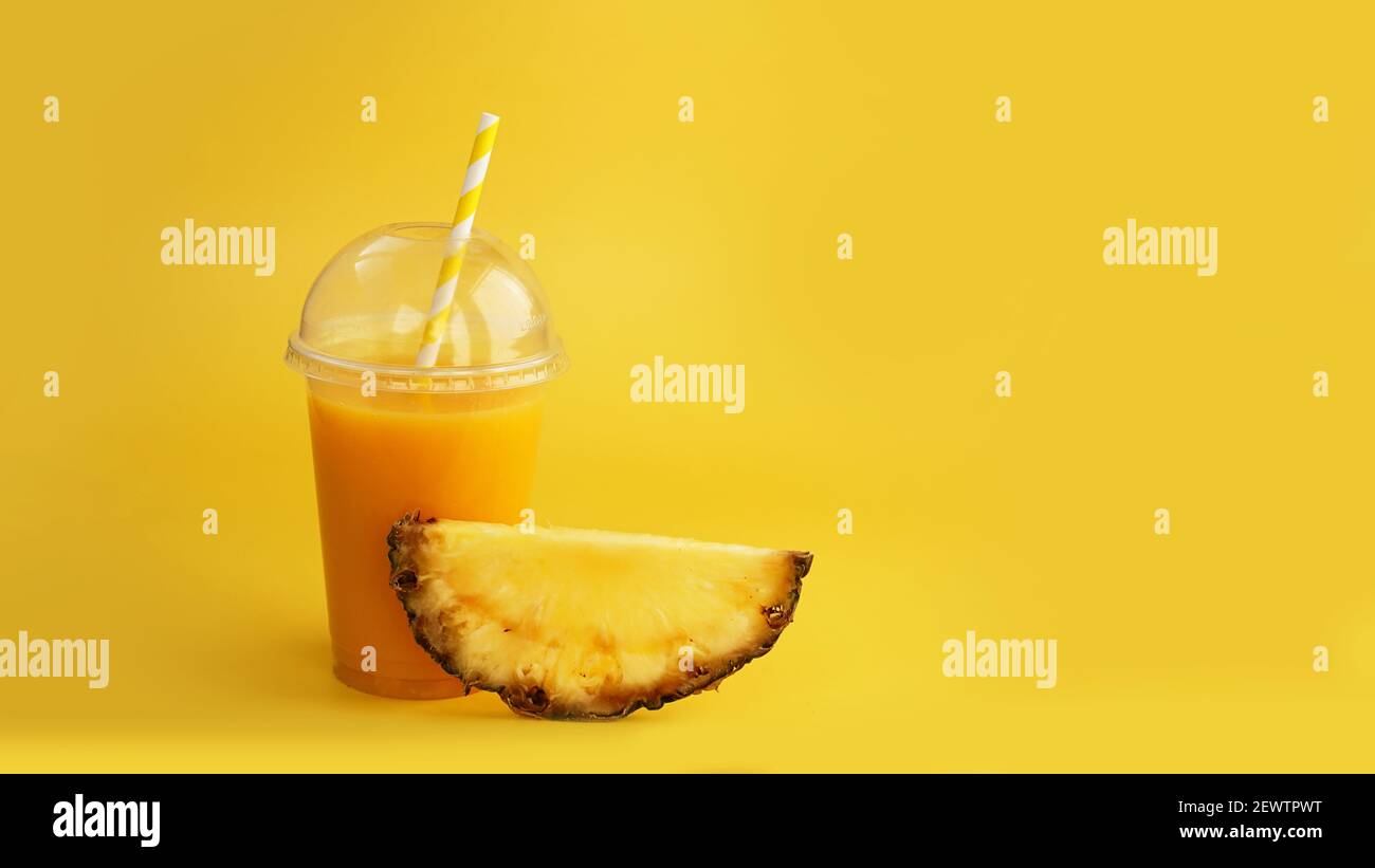 Pineapple juice in a plastic cup on yellow background Stock Photo