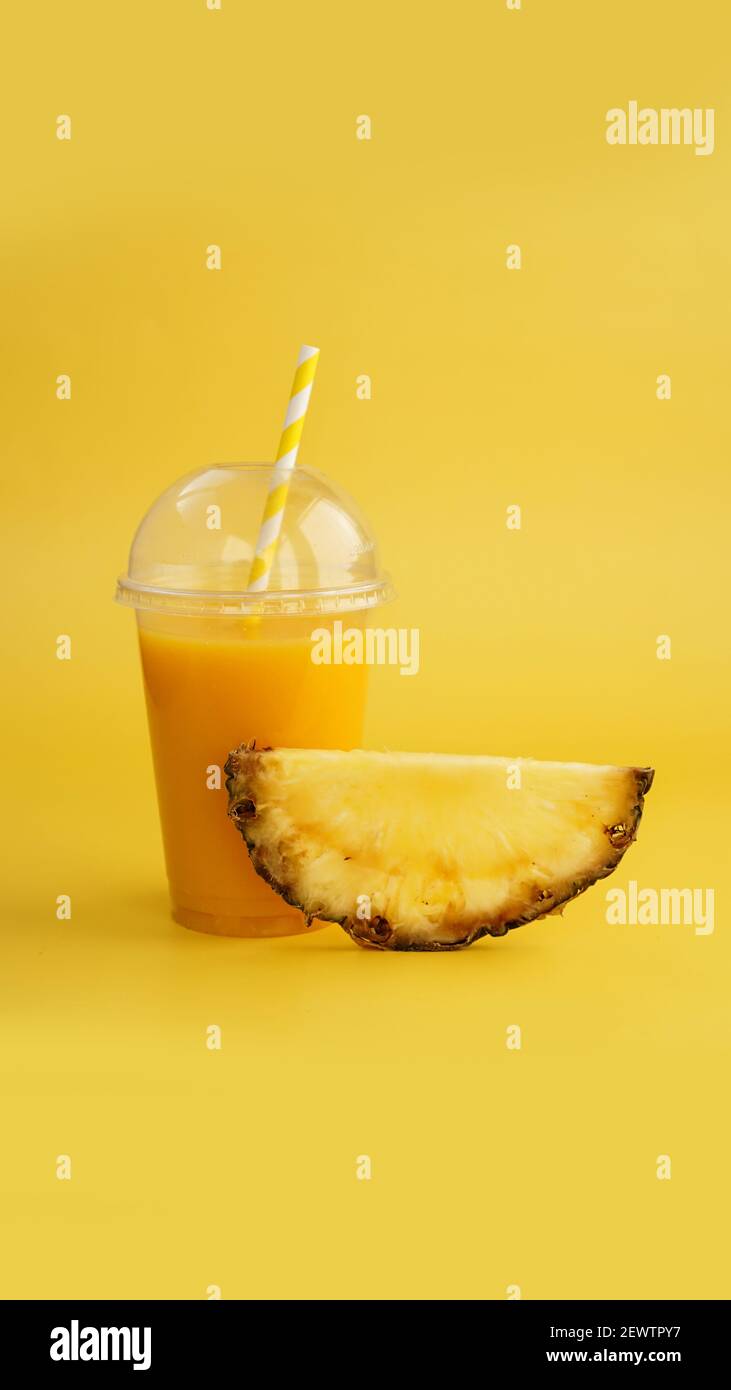 Pineapple juice in a plastic cup on yellow background Stock Photo