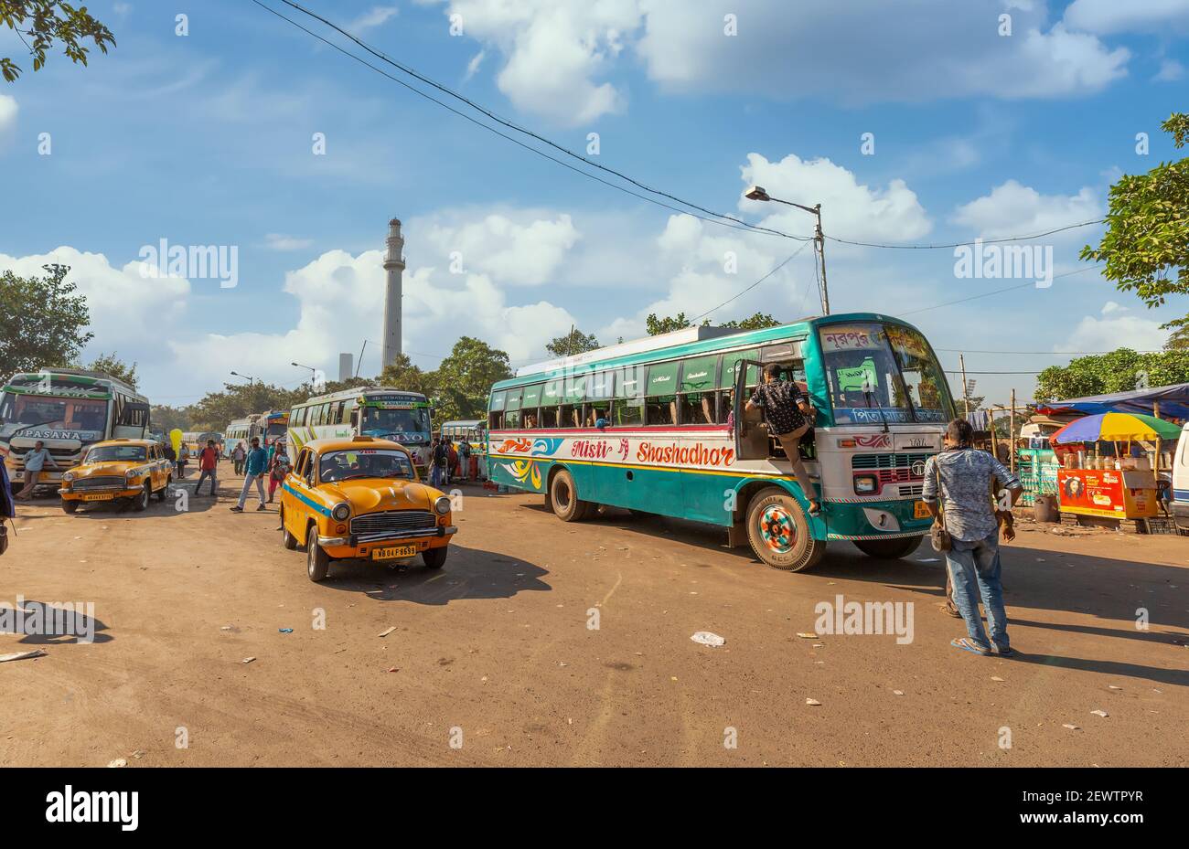 Yellow taxi with public transport busses at city bus terminal with view of historic Shaheed Minar at Kolkata India Stock Photo