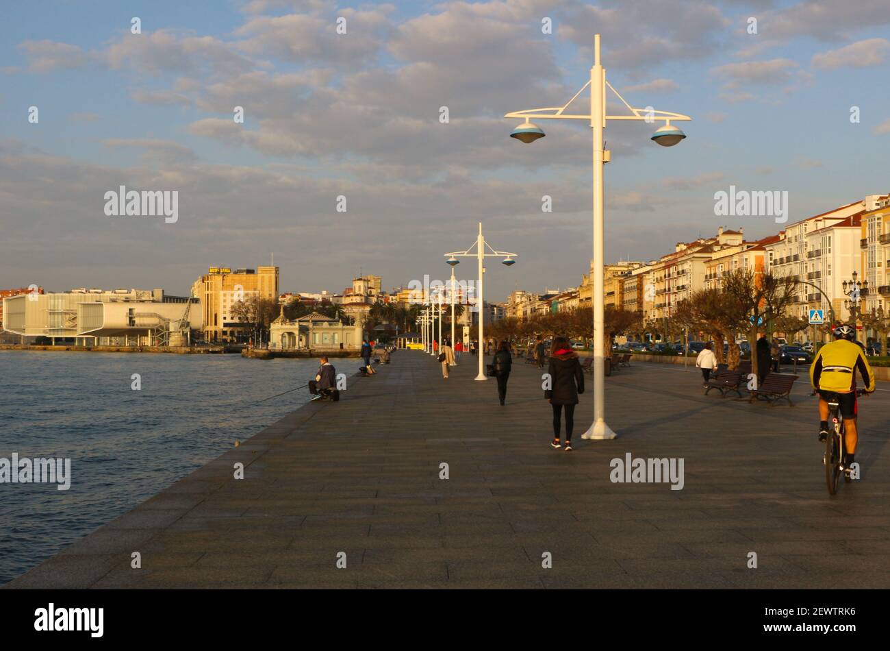 Morning exercise with people walking a cyclist and rod and line fishing Santander bay Cantabria Spain in winter sun city centre during pandemic Stock Photo