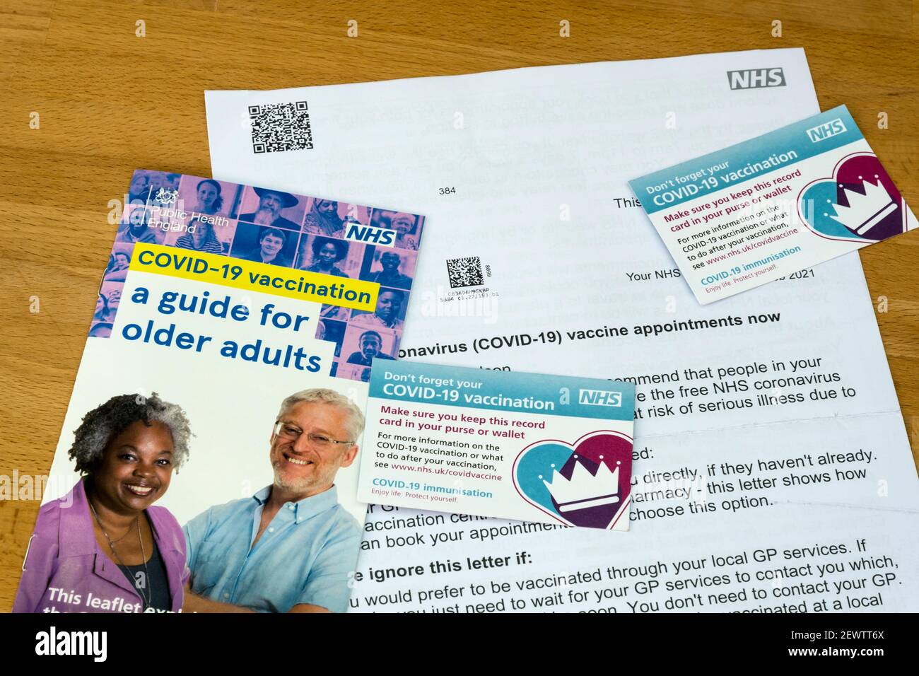 A NHS guide & letter inviting to Covid-19 vaccinations for older adults, with two Covid-19 vaccination record cards. Stock Photo