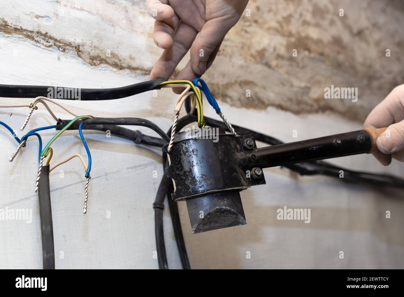 An electrician solders twisted electrical wires in a house under