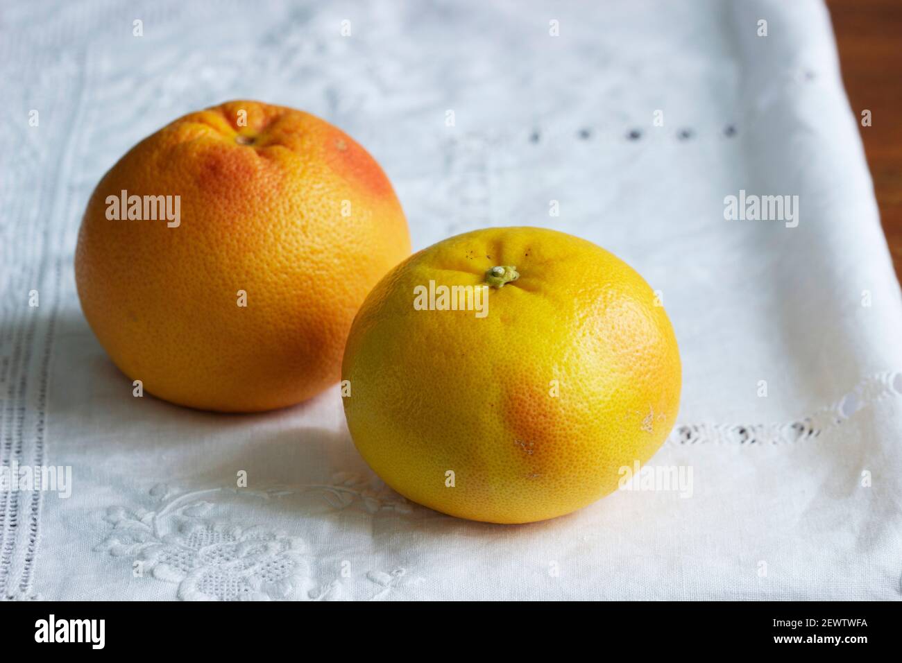 Ripe grapefruits on a white screwed tablecloth. Stock Photo