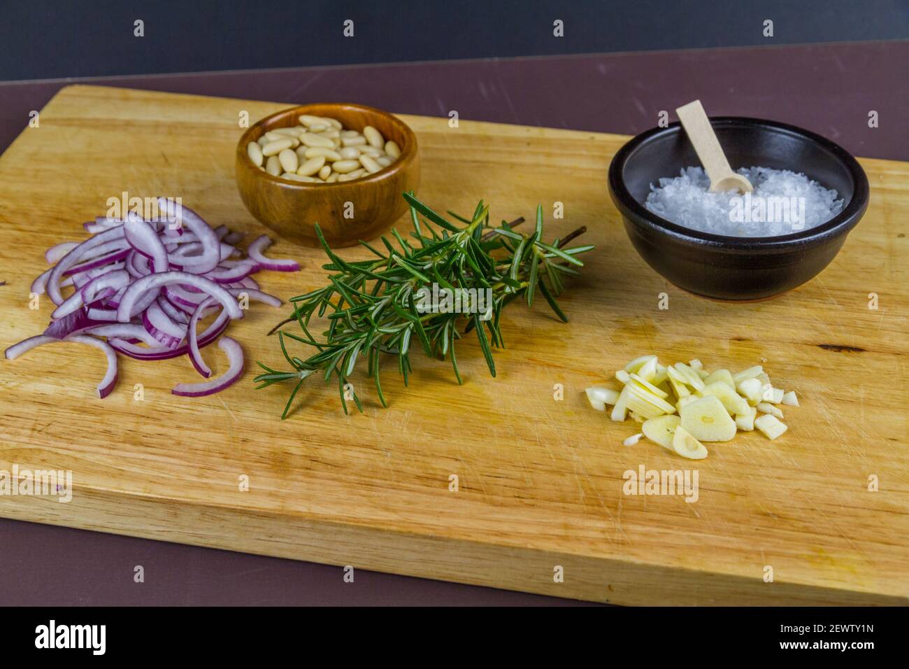 Wood wooden board with onion, rosemary, salt and pine nuts, bowl, pile