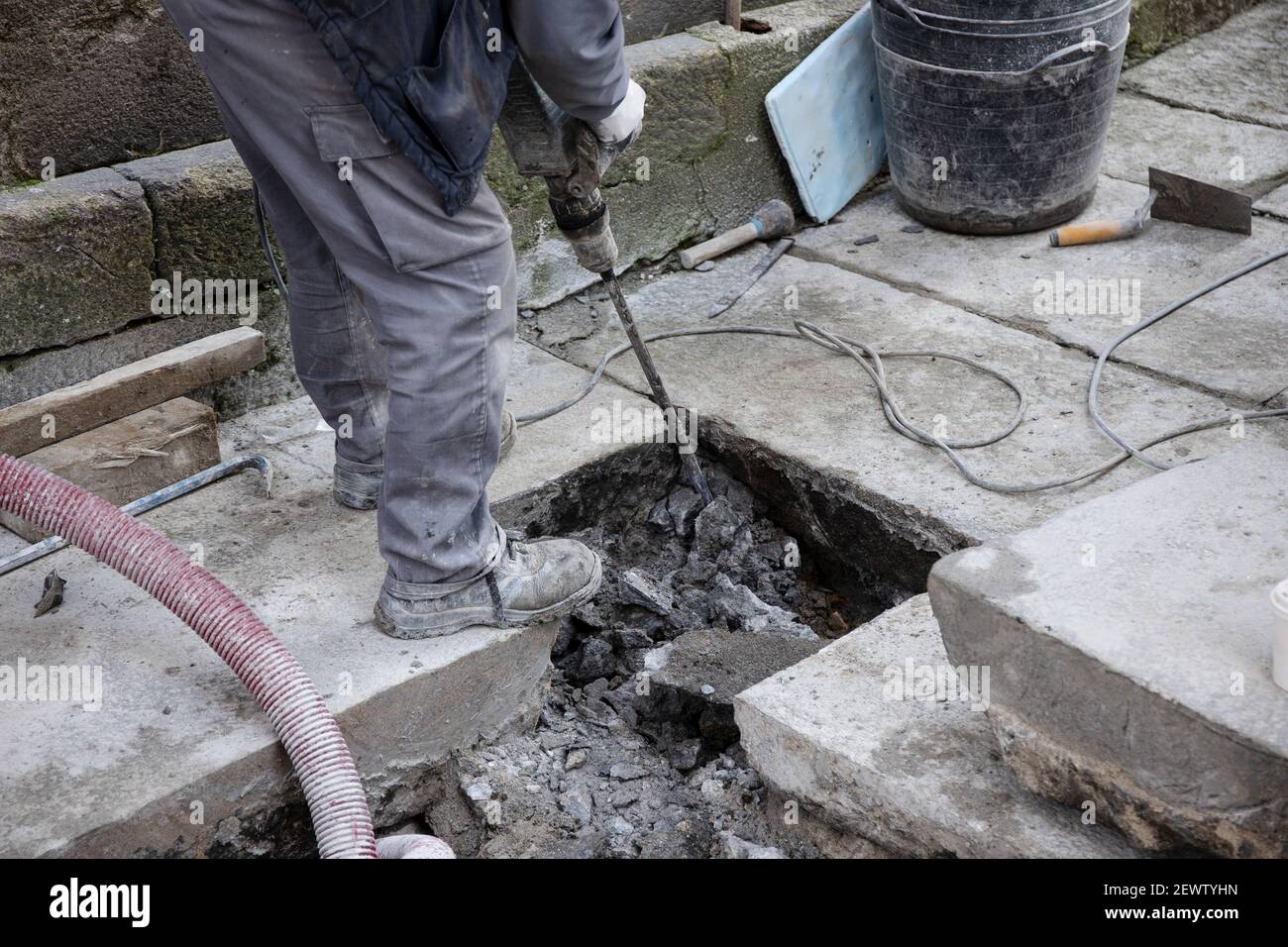 Construction worker with jackhammer working on old paving stone street