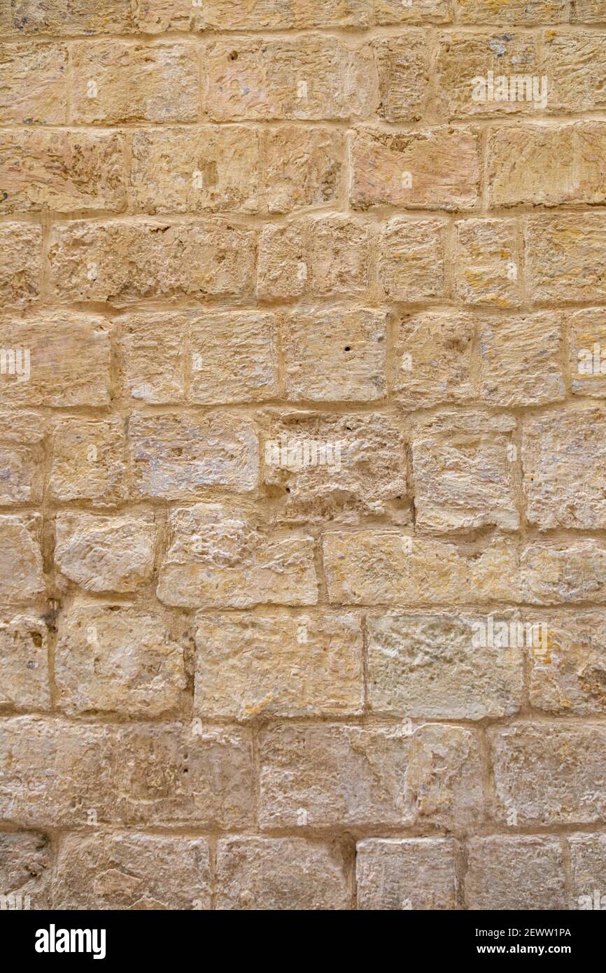 deteriorated, textured, aged, golden yellow brick-shaped stone wall Stock Photo
