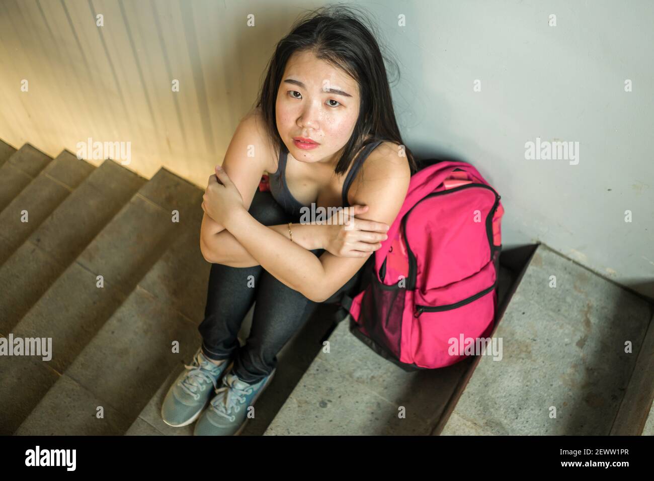 young depressed and scared Asian Chinese student girl suffering abuse and  harassment at school victim of bullying and discrimination sitting on  colleg Stock Photo - Alamy