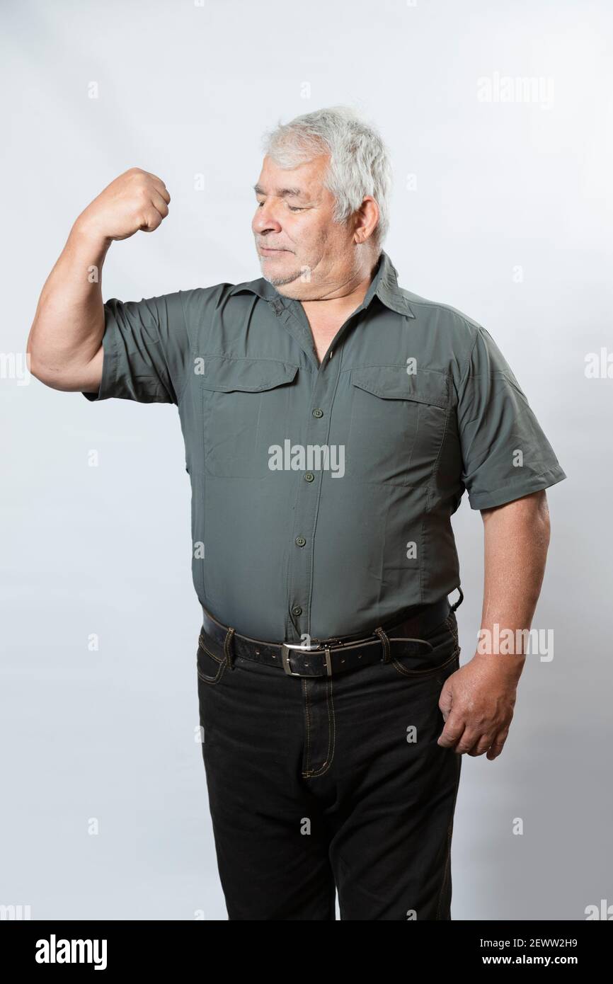 Strong senior man showing his arm muscles. Happy Hispanic elderly man