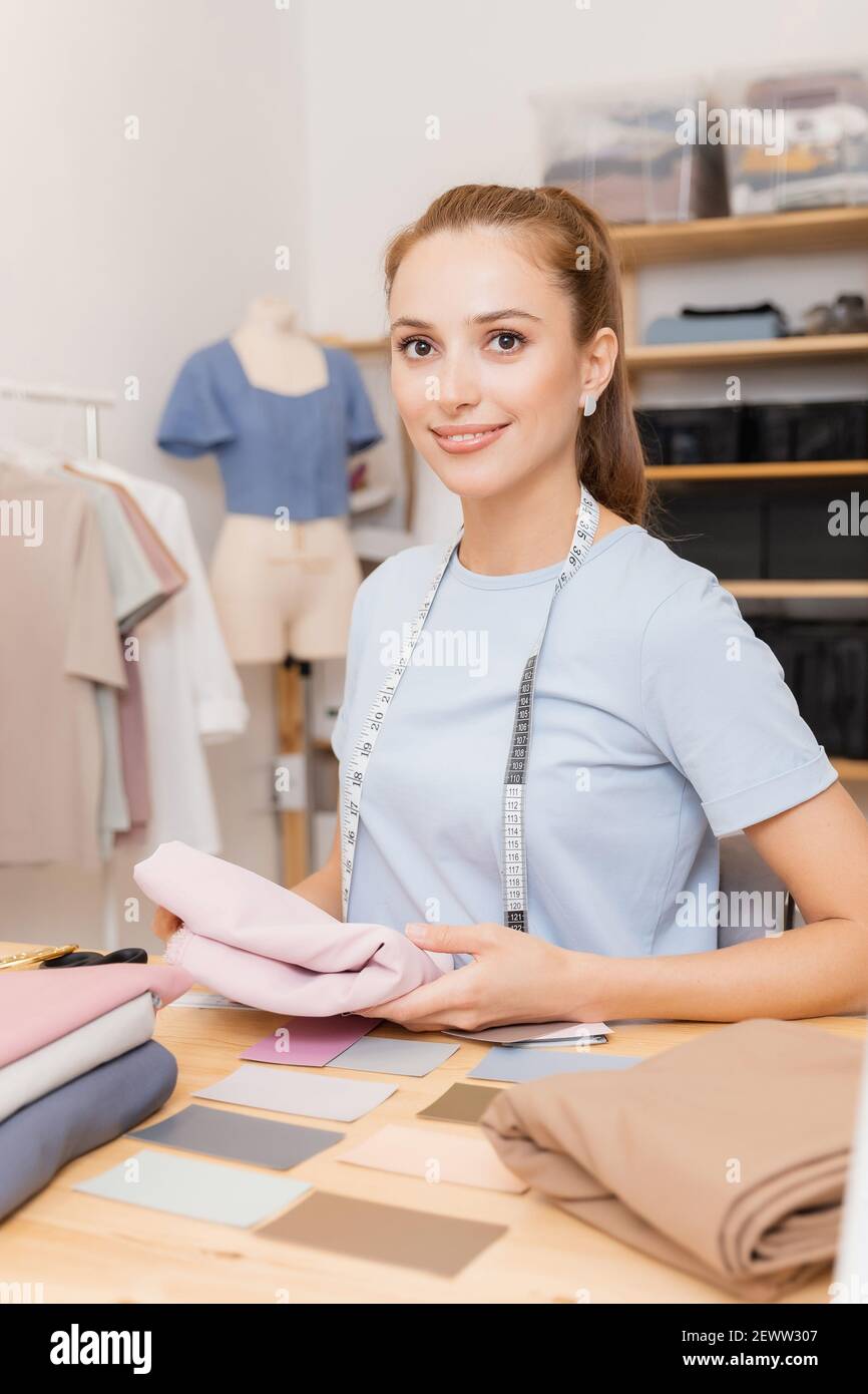 Female designer dressmaker working on sewing machine in studio. Forms