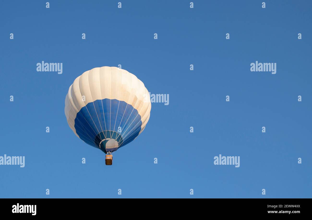 Blue and white hot air balloon flying in blue sky with room for text ...