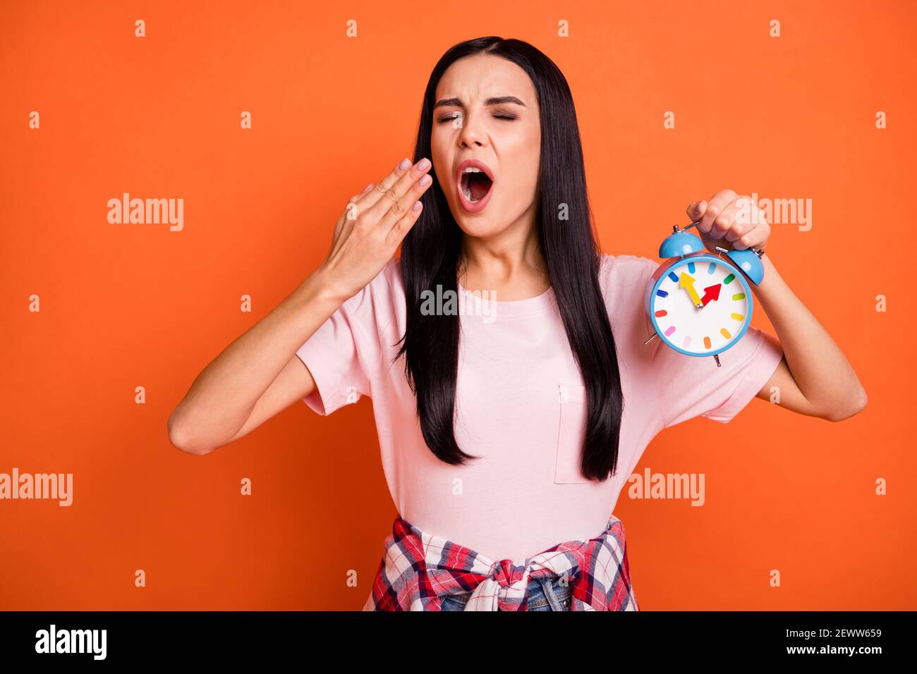 Photo of young lady arm hold clock closed eyes open mouth yawn feel sleepy isolated on orange color background Stock Photo