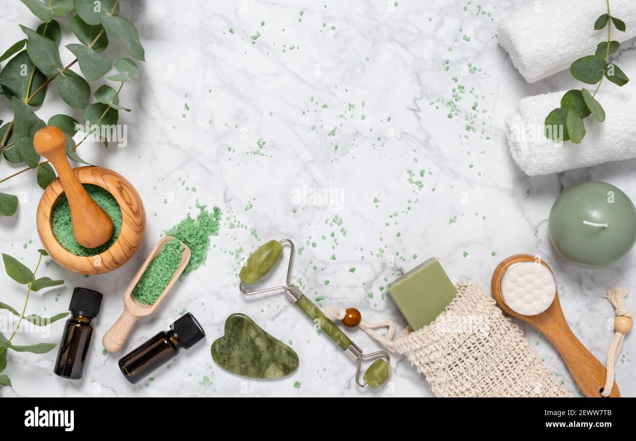 Natural skin care and aromatherapy with eucalyptus essential oil bottles, bath salt, beauty jade roller, gua sha on marble. Spa, wellness, massage and Stock Photo