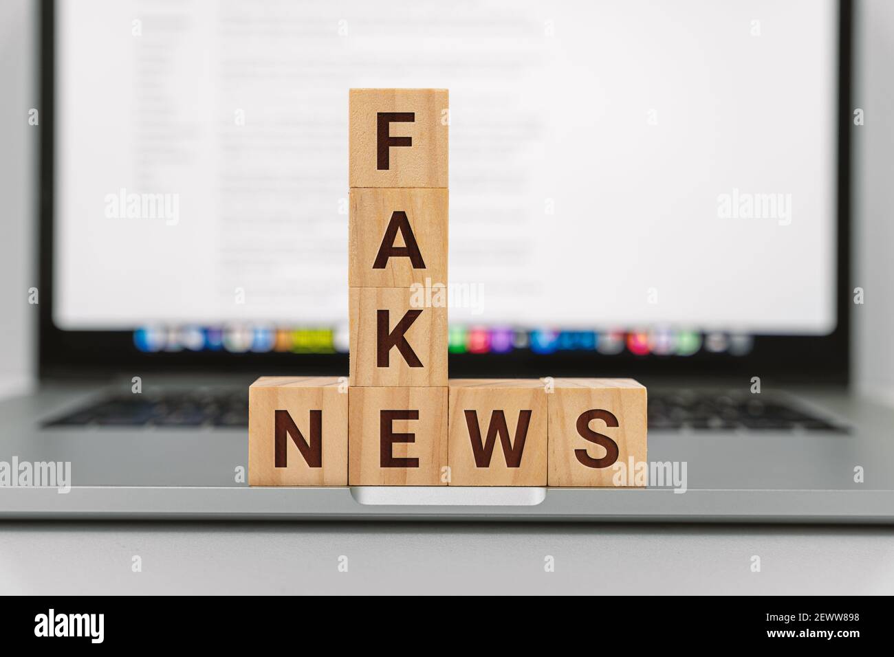 Fake News on Wooden Block Against Laptop Screen Stock Photo