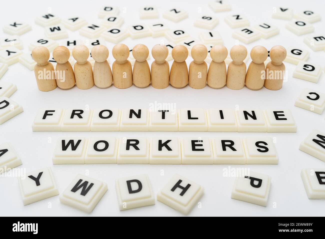 Frontline Workers Words With Line of Wooden Peg Doll Figurines on White Background Stock Photo