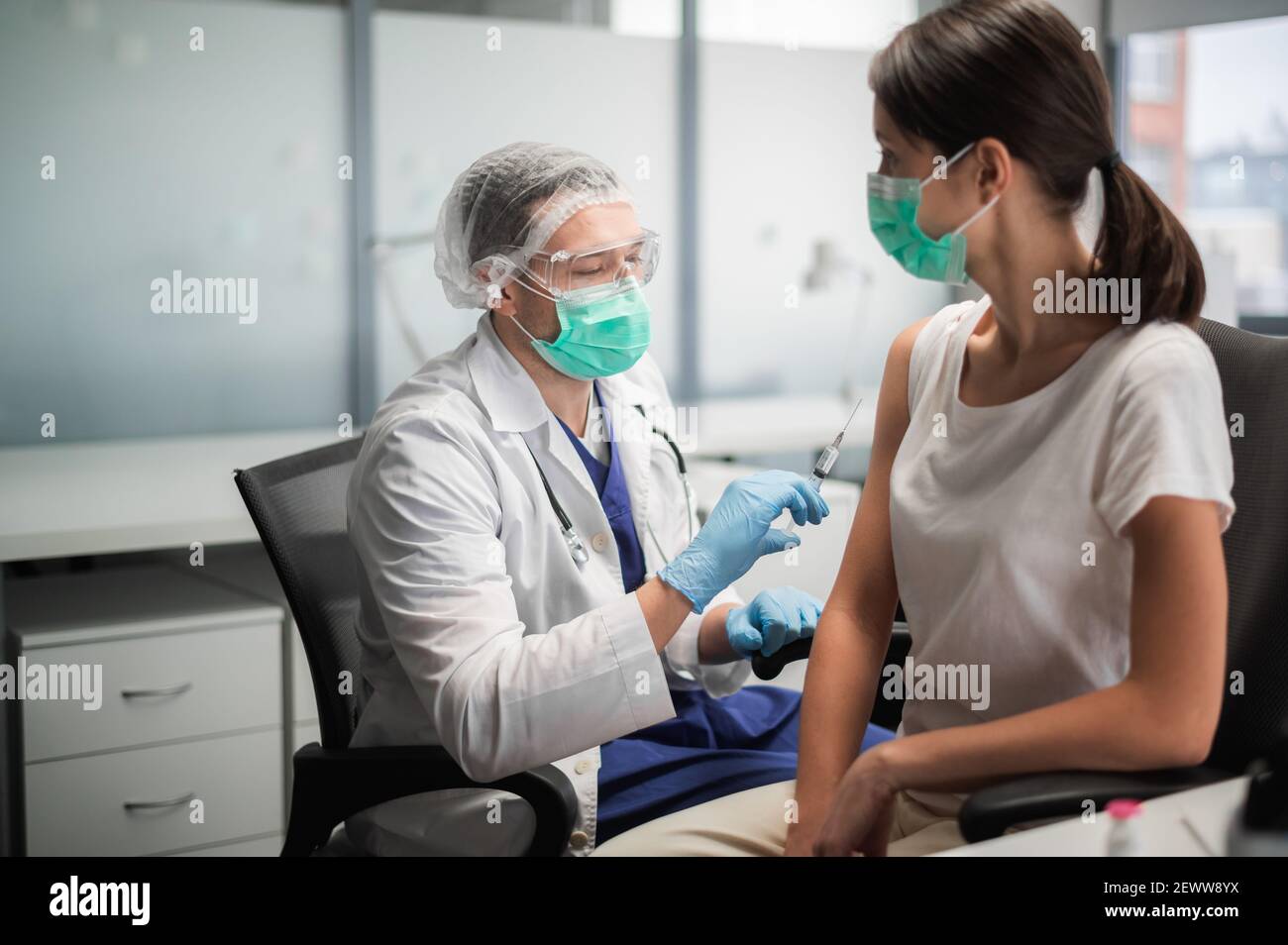 An experienced doctor in a mask does the vaccination in his office in a