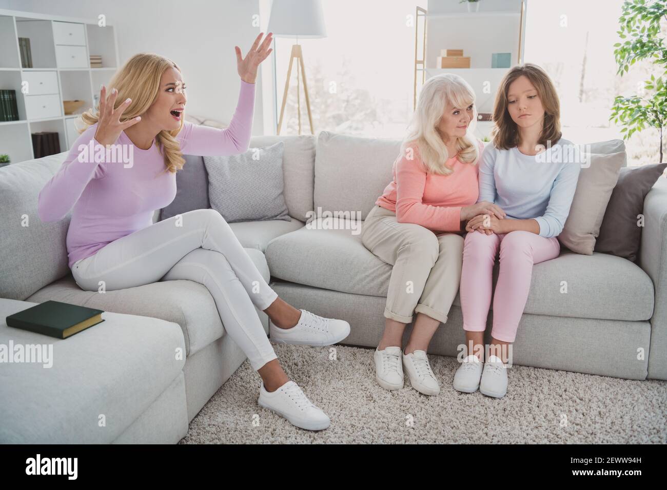 Photo portrait of granny caring about sad granddaughter sitting near angry daughter arguing misunderstanding Stock Photo