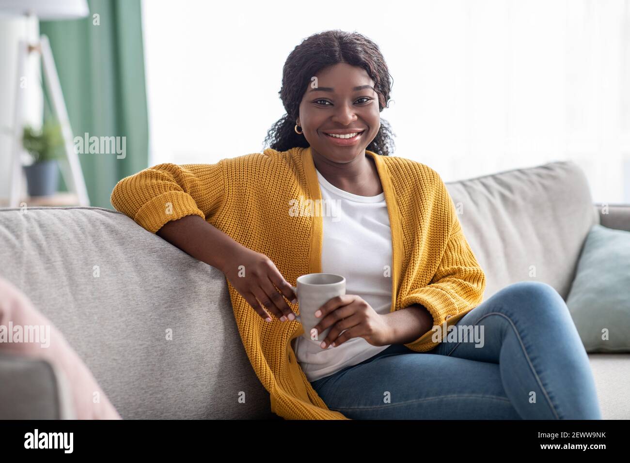 Cheerful black woman drinking coffee at home Stock Photo - Alamy