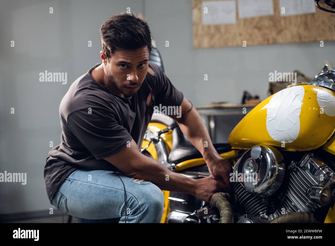 A handsome young male biker in his garage is preparing his motorcycle for  the season. Repair and tuning Stock Photo - Alamy