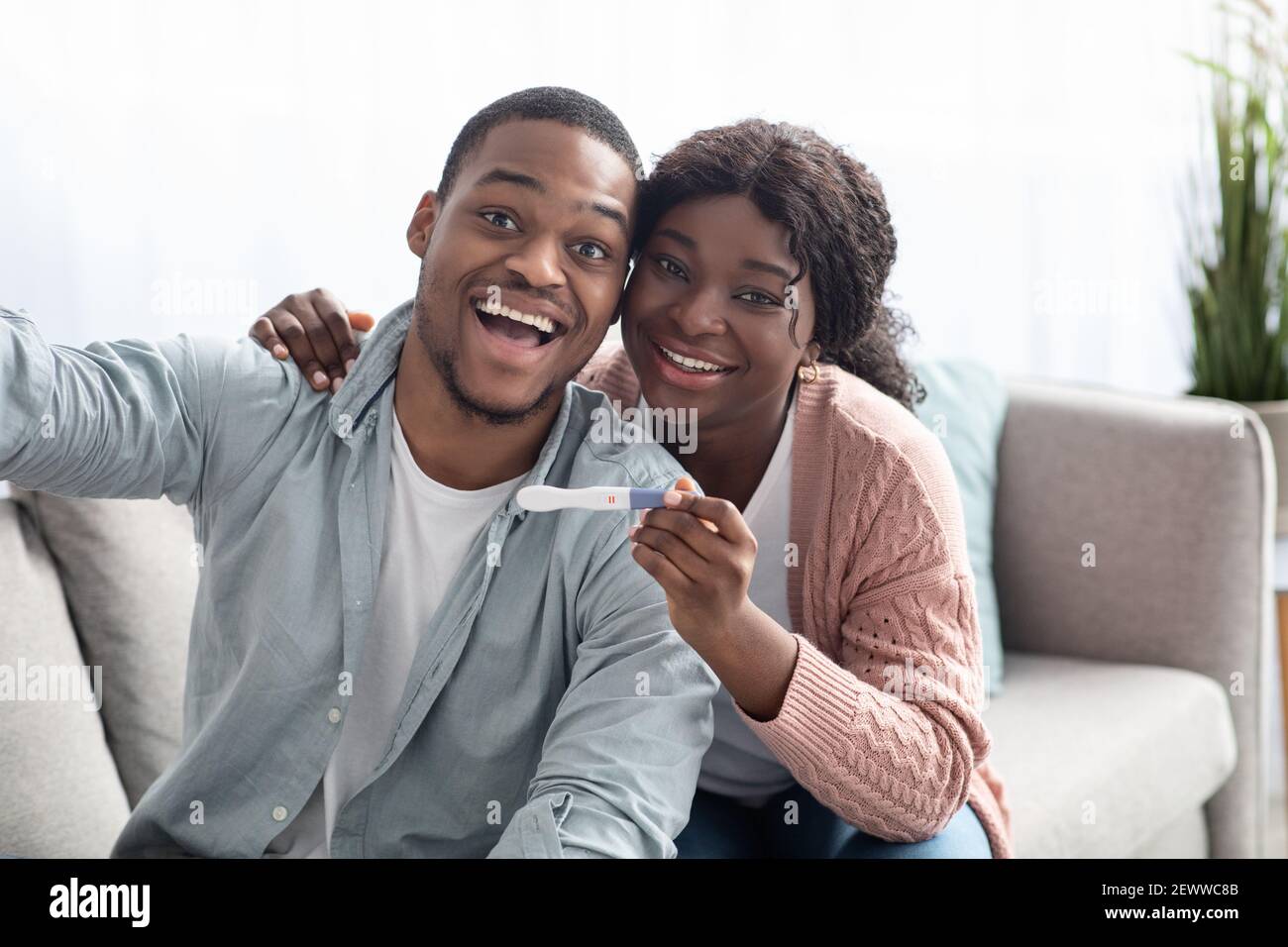 Happy black couple with positive pregnancy test taking selfie Stock Photo